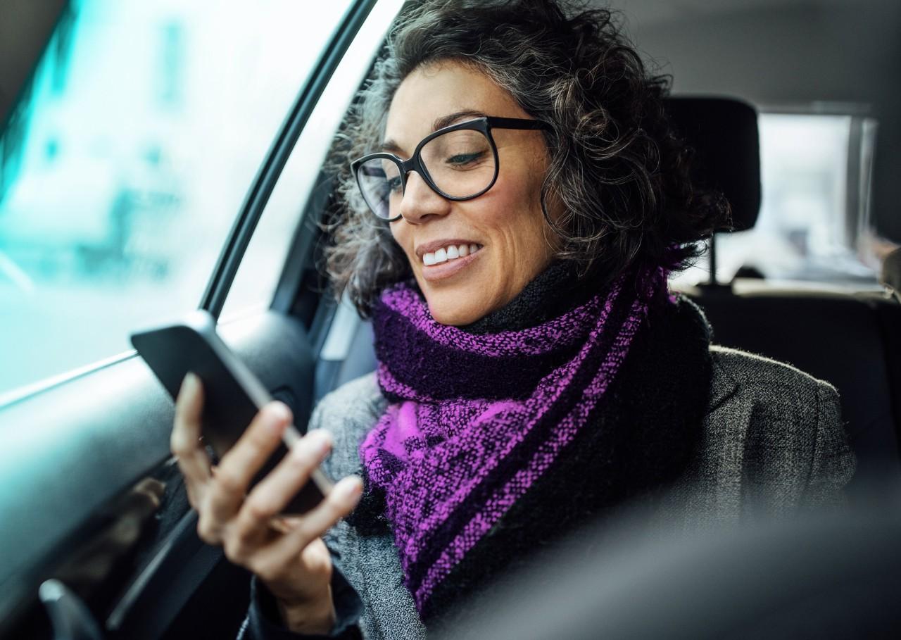 成熟的女人在车里看她的智能手机 